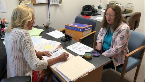 Picture of caseworker with client filling out paperwork